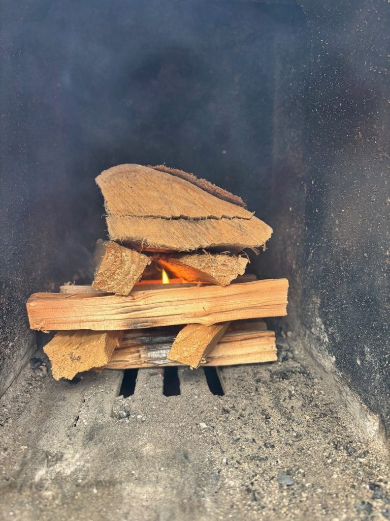 Kindling and split logs catching alight in a wood-fired hot tub stove firebox